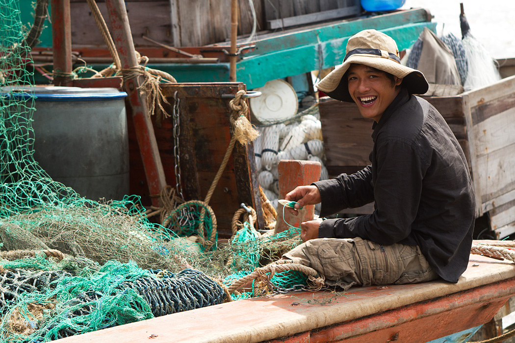 Fisherman fixing his net on a boat near Mui Ca Mau, Vietnam.