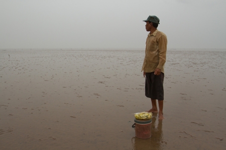 A local man returns from collecting small fish and crustaceans in the mudflats.