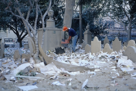 A rescue worker tries to remove dust from an American flag on the debris covered cemetery of St. Paul's Chapel