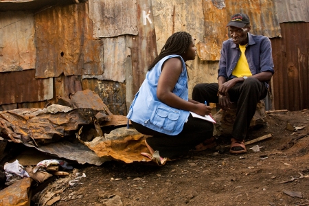 Community volunteer Triza Awino interviews a man who lost his home to a fire in Kibera Slum, Nairobi